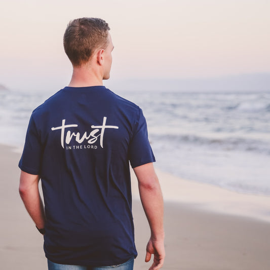 Man wearing a Navy T-shirt with the words: "Trust in the Lord", walking on the beach.
