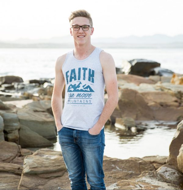 Man on the beach wearing grey melange Christian vest with the words "Faith can move mountains"