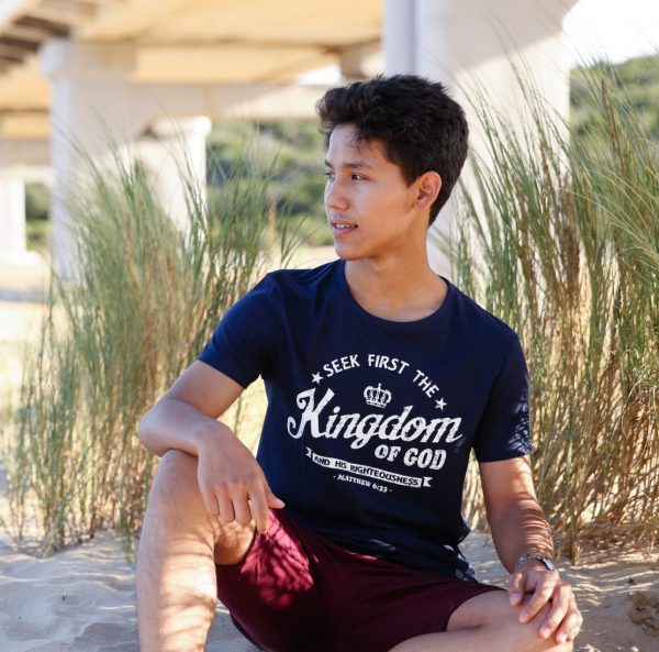 Young man on beach wearing navy blue Christian T shirt with white words "Seek first the kingdom of God"