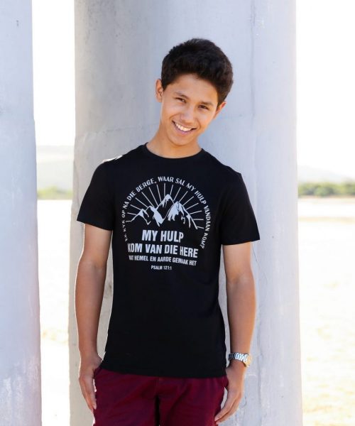 Young man on beach wearing black Christian T shirt with the words "My hulp kom van die Here wat hemel en aarde gemaak het"