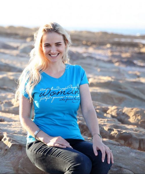 Lady on beach wearing turquoise Christian ladies T shirt with the words of Proverbs 31